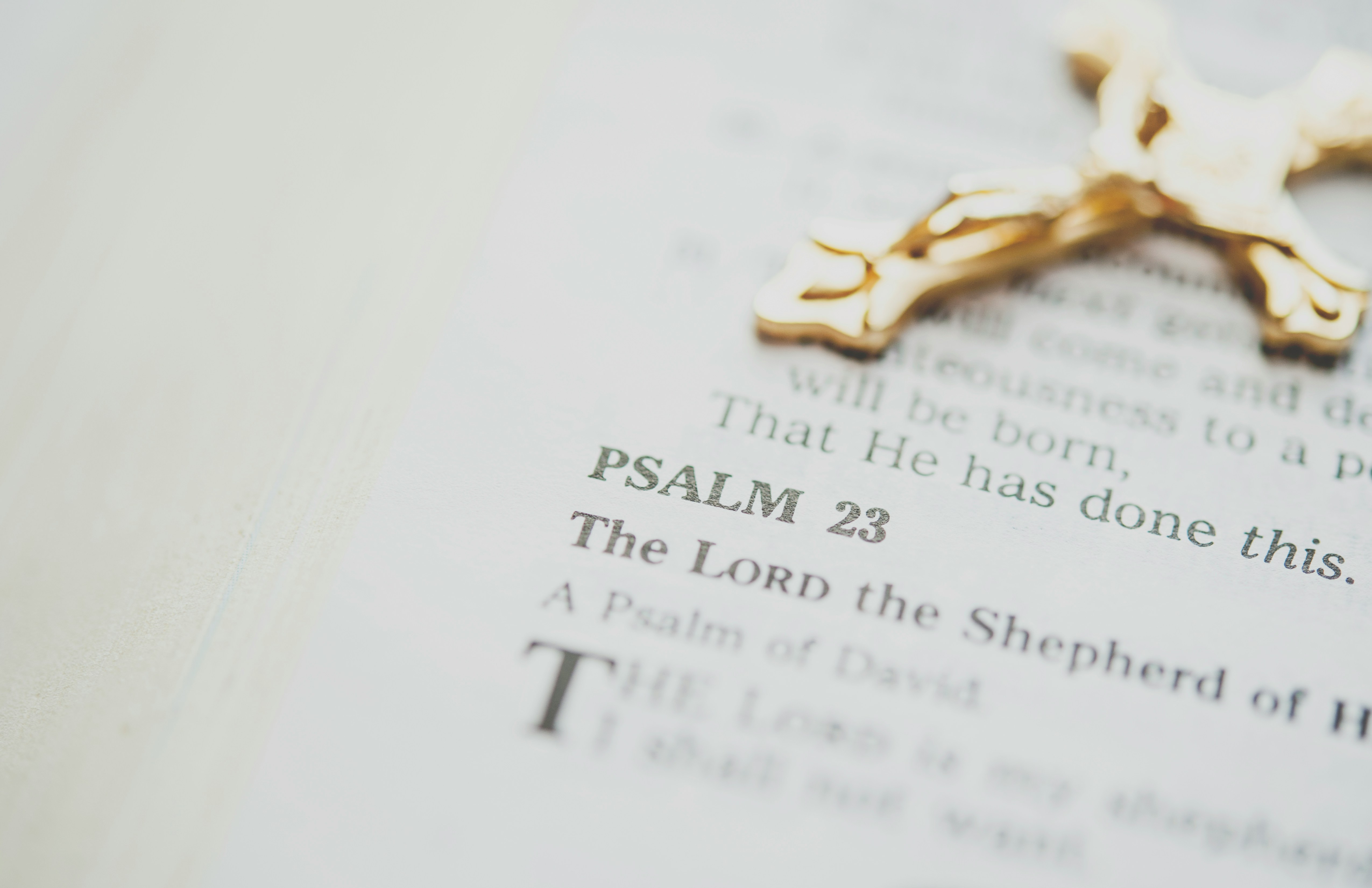 Close-up photo of a gold crucifix on a page of Scripture opened to Psalm 23