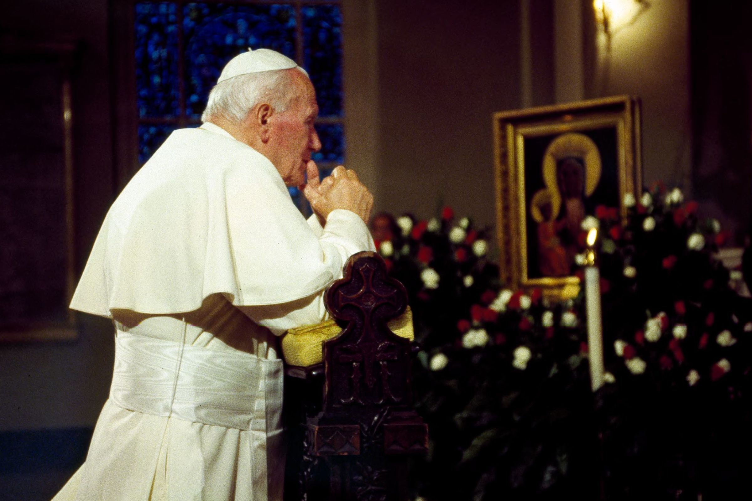 Pope John Paul II kneeling in prayer before an image of Jesus and Mary