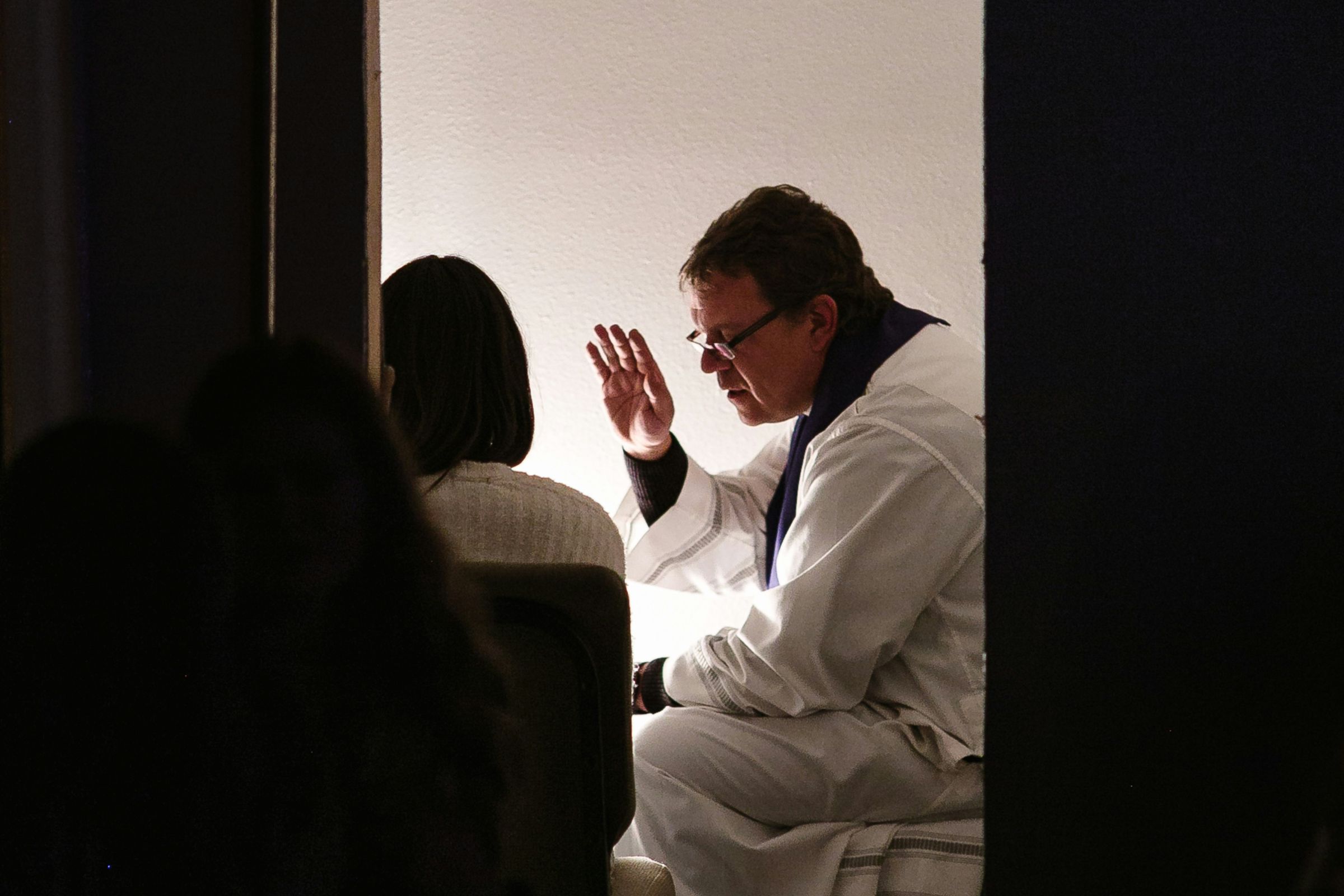 Catholic priest giving absolution to a penitent in the confessional