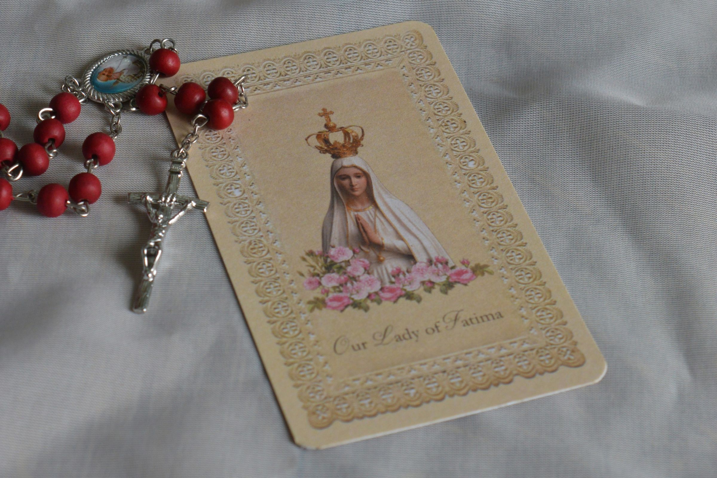 Red rosary beads with a prayer card of Our Lady of Fatima