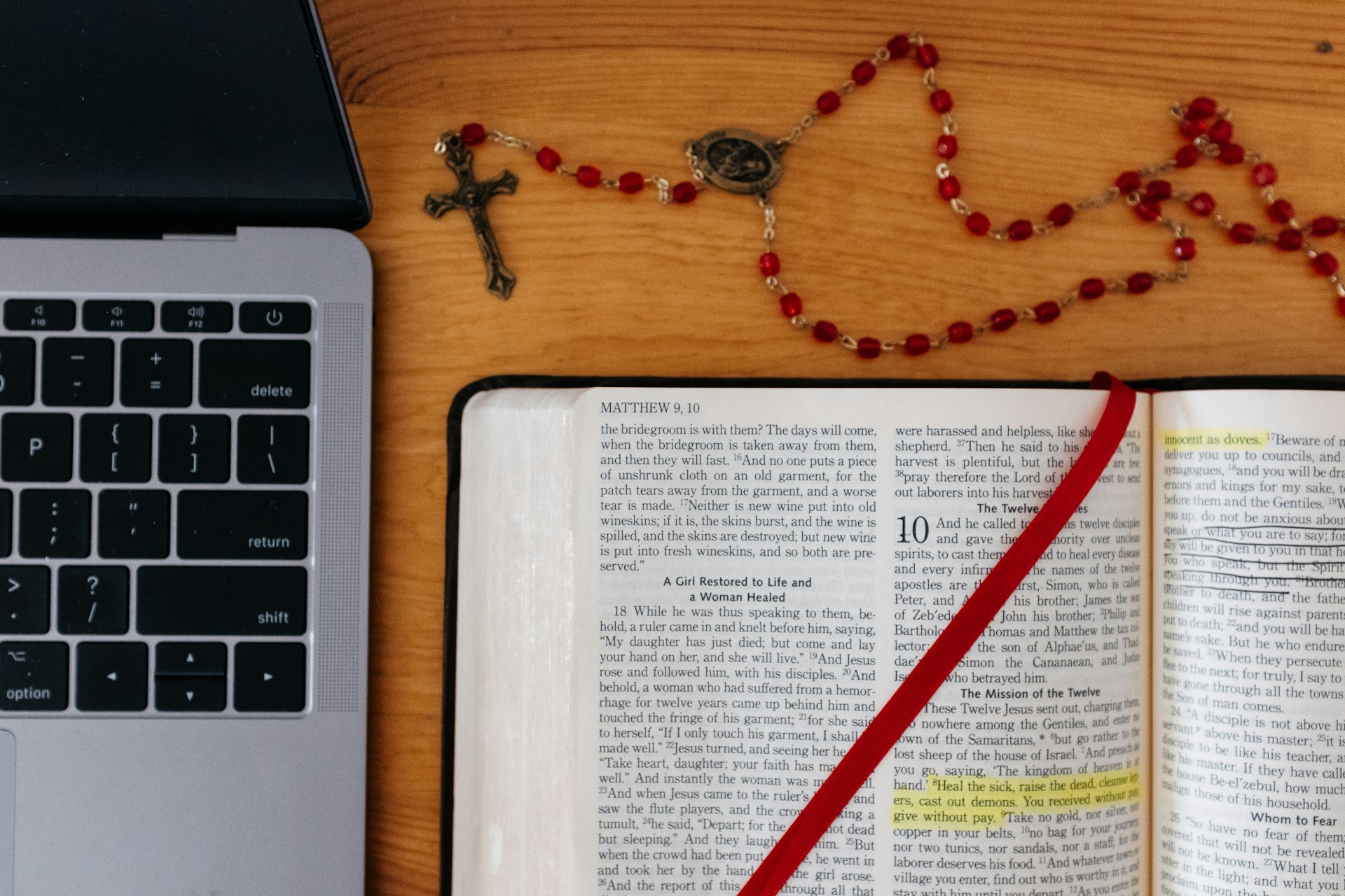 Open Bible with a laptop and set of rosary beads