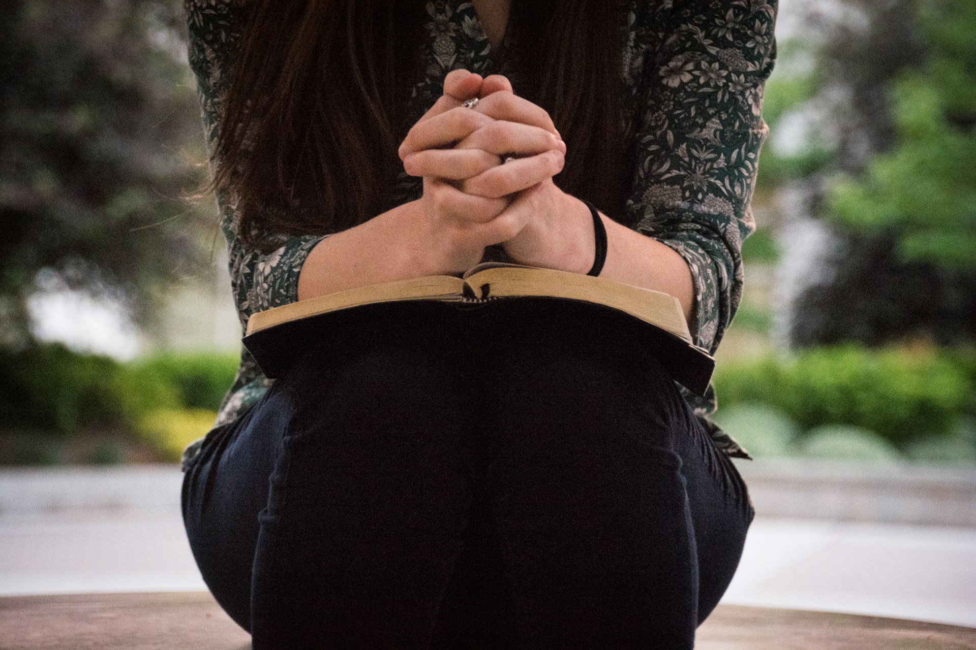 Young woman praying with an open Bible on her lap