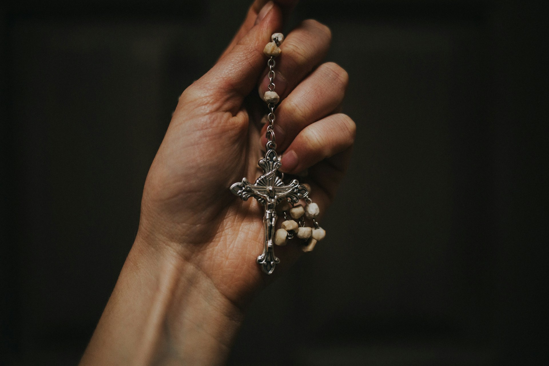 A hand holding rosary beads with a crucifix