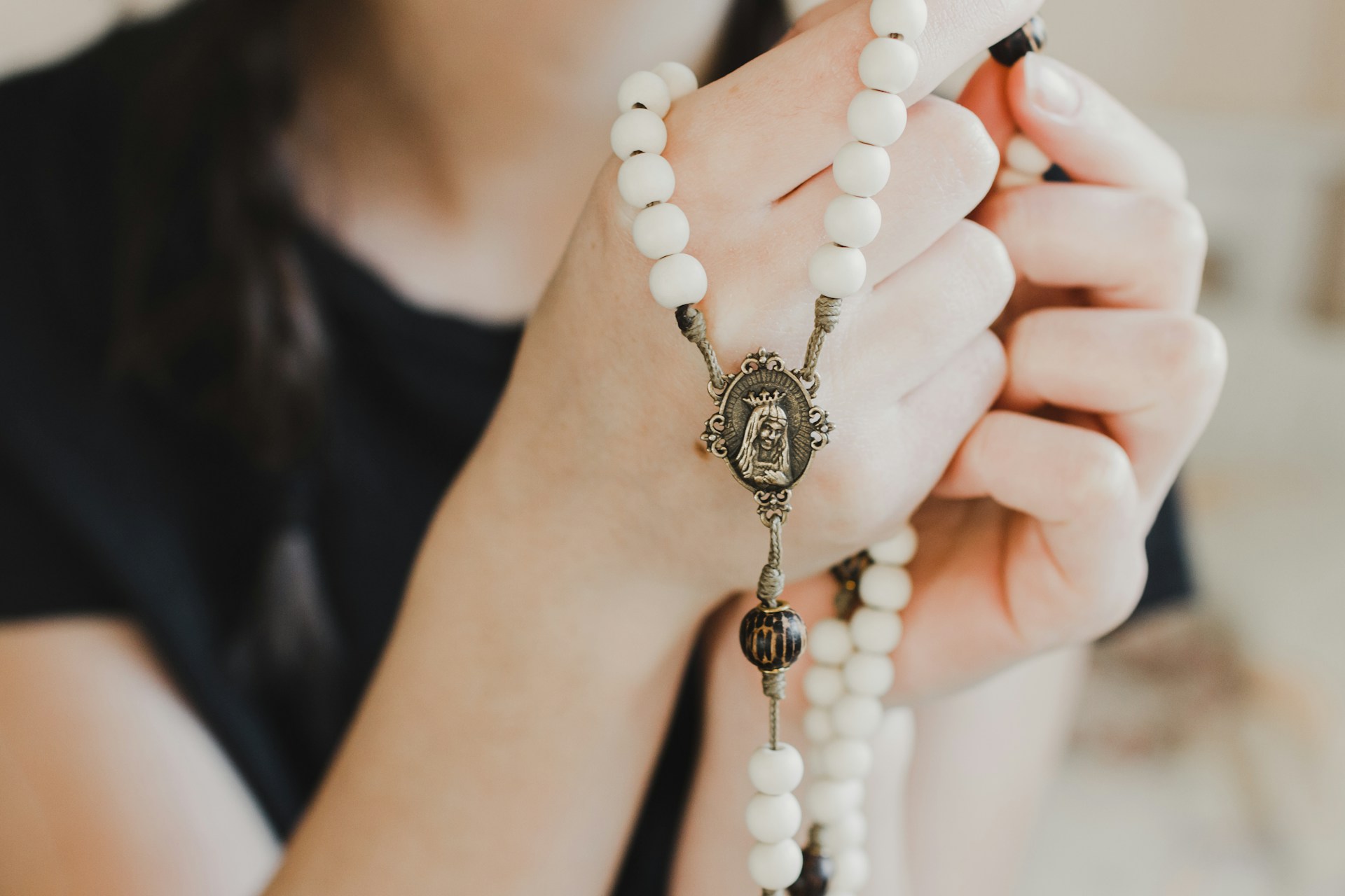 Woman praying with a set of white rosary beads